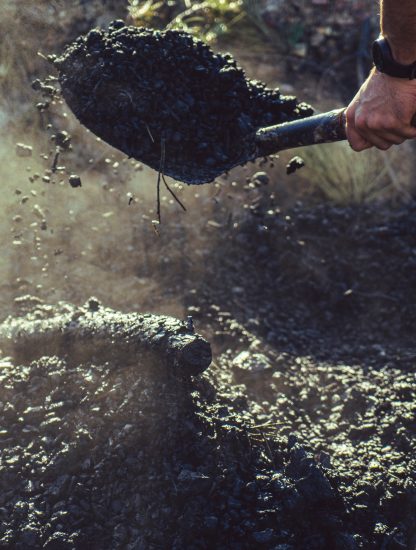Une personne pelle du charbon de bois au soleil du matin, biochar. Photo Shutterstock